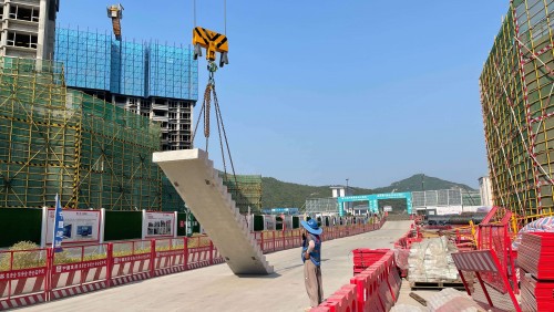 Workers use a crane to lift a prefabricated staircase for positioning and installation.