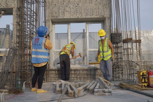 Workers install a prefabricated façade panel.